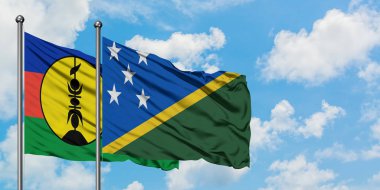 Yeni Kaledonya ve Solomon Adaları bayrağı birlikte beyaz bulutlu mavi gökyüzüne karşı rüzgarda sallayarak. Diplomasi kavramı, uluslararası ilişkiler.