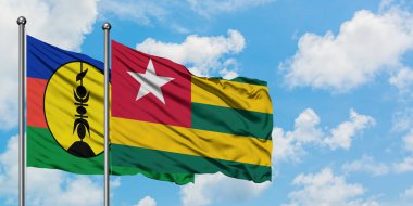 Yeni Kaledonya ve Togo bayrağı birlikte beyaz bulutlu mavi gökyüzüne karşı rüzgarda sallayarak. Diplomasi kavramı, uluslararası ilişkiler.