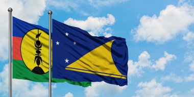 Yeni Kaledonya ve Tokelau bayrağı birlikte beyaz bulutlu mavi gökyüzüne karşı rüzgarda sallayarak. Diplomasi kavramı, uluslararası ilişkiler.