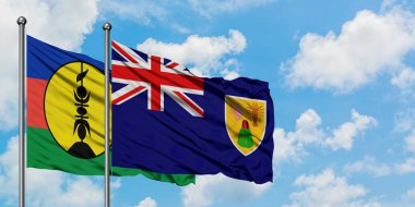 Yeni Kaledonya ve Turks ve Caicos Adaları bayrağı birlikte beyaz bulutlu mavi gökyüzüne karşı rüzgarda sallayarak. Diplomasi kavramı, uluslararası ilişkiler.