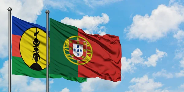 Bandera de Nueva Caledonia y Portugal ondeando en el viento contra el cielo azul nublado blanco juntos. Concepto diplomático, relaciones internacionales . —  Fotos de Stock