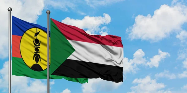 Bandera de Nueva Caledonia y Sudán ondeando en el viento contra el cielo azul nublado blanco juntos. Concepto diplomático, relaciones internacionales . — Foto de Stock