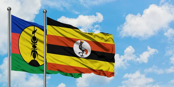 New Caledonia and Uganda flag waving in the wind against white cloudy blue sky together. Diplomacy concept, international relations. — Stock Photo, Image