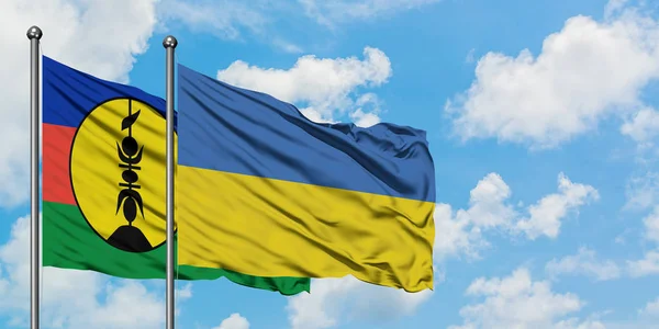 Nouvelle-Calédonie et l'Ukraine drapeau agitant dans le vent contre ciel bleu nuageux blanc ensemble. Concept de diplomatie, relations internationales . — Photo