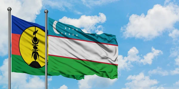 Bandera de Nueva Caledonia y Uzbekistán ondeando en el viento contra el cielo azul nublado blanco juntos. Concepto diplomático, relaciones internacionales . — Foto de Stock