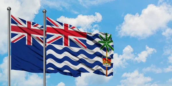 Bandera de Nueva Zelanda y del Territorio Británico del Océano Índico ondeando en el viento contra el cielo azul nublado blanco juntos. Concepto diplomático, relaciones internacionales . — Foto de Stock