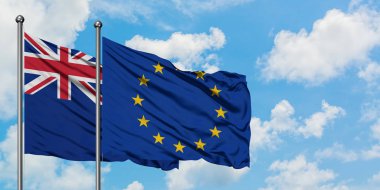 Yeni Zelanda ve Avrupa Birliği bayrağı birlikte beyaz bulutlu mavi gökyüzüne karşı rüzgarda sallayarak. Diplomasi kavramı, uluslararası ilişkiler.