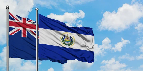 Bandera de Nueva Zelanda y El Salvador ondeando en el viento contra el cielo azul nublado blanco juntos. Concepto diplomático, relaciones internacionales . — Foto de Stock
