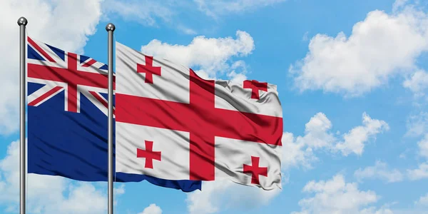Bandera de Nueva Zelanda y Georgia ondeando en el viento contra el cielo azul nublado blanco juntos. Concepto diplomático, relaciones internacionales . — Foto de Stock