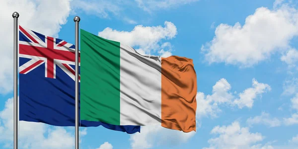 Drapeau de la Nouvelle-Zélande et de l'Irlande agitant dans le vent contre ciel bleu nuageux blanc ensemble. Concept de diplomatie, relations internationales . — Photo