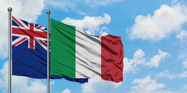 Bandera de Nueva Zelanda e Italia ondeando en el viento contra el cielo azul nublado blanco juntos. Concepto diplomático, relaciones internacionales . — Foto de Stock