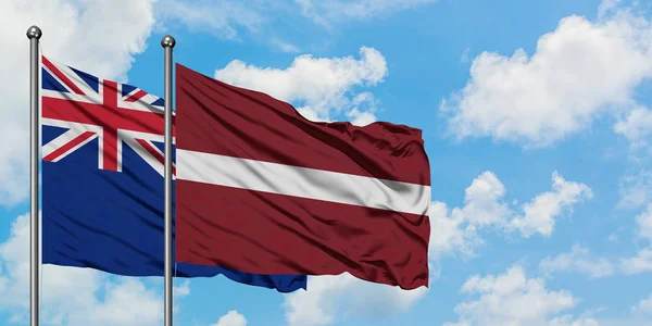 Drapeau de la Nouvelle-Zélande et de la Lettonie agitant dans le vent contre ciel bleu nuageux blanc ensemble. Concept de diplomatie, relations internationales . — Photo