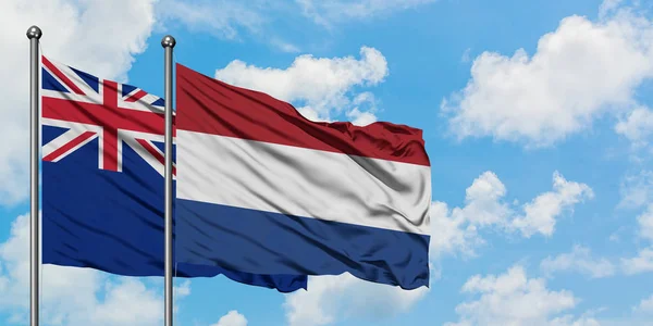 Nowa Zelandia i Holandia flaga machając w wiatr przed białym zachmurzone błękitne niebo razem. Koncepcja dyplomacji, stosunki międzynarodowe. — Zdjęcie stockowe