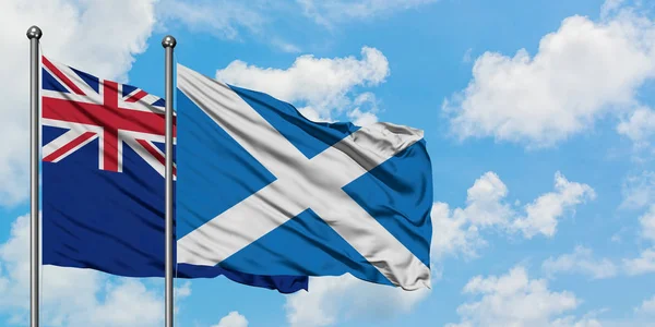 Bandera de Nueva Zelanda y Escocia ondeando en el viento contra el cielo azul nublado blanco juntos. Concepto diplomático, relaciones internacionales . — Foto de Stock