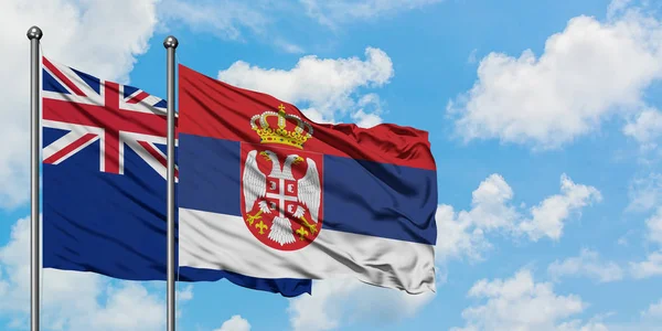 Nový Zéland a srbská vlajka mávali ve větru proti bíle zatažené modré obloze. Diplomacie, mezinárodní vztahy. — Stock fotografie