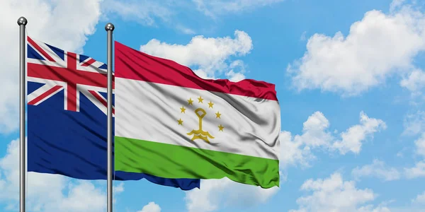 Bandera de Nueva Zelanda y Tayikistán ondeando en el viento contra el cielo azul nublado blanco juntos. Concepto diplomático, relaciones internacionales . — Foto de Stock