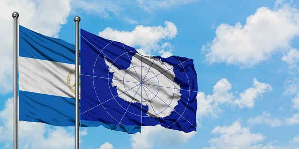 Nicaragua und die Antarktis-Flagge wehen gemeinsam im Wind vor dem wolkenverhangenen blauen Himmel. Diplomatie-Konzept, internationale Beziehungen. — Stockfoto