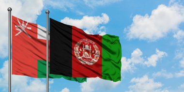 Umman ve Afganistan bayrağı birlikte beyaz bulutlu mavi gökyüzüne karşı rüzgarda sallayarak. Diplomasi kavramı, uluslararası ilişkiler.