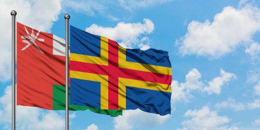 Umman ve Aland Adaları bayrağı birlikte beyaz bulutlu mavi gökyüzüne karşı rüzgarda sallayarak. Diplomasi kavramı, uluslararası ilişkiler.