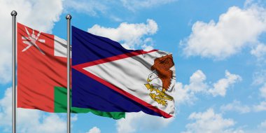 Umman ve Amerikan Samoası bayrağı birlikte beyaz bulutlu mavi gökyüzüne karşı rüzgarda sallayarak. Diplomasi kavramı, uluslararası ilişkiler.