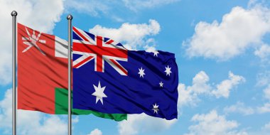 Umman ve Avustralya bayrağı birlikte beyaz bulutlu mavi gökyüzüne karşı rüzgarda sallayarak. Diplomasi kavramı, uluslararası ilişkiler.