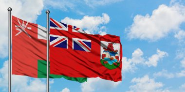 Umman ve Bermuda bayrağı birlikte beyaz bulutlu mavi gökyüzüne karşı rüzgarda sallayarak. Diplomasi kavramı, uluslararası ilişkiler.