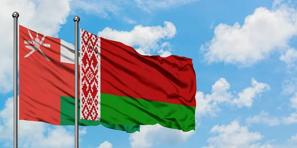 Bandera de Omán y Bielorrusia ondeando en el viento contra el cielo azul nublado blanco juntos. Concepto diplomático, relaciones internacionales . — Foto de Stock