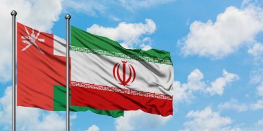 Umman ve İran bayrağı birlikte beyaz bulutlu mavi gökyüzüne karşı rüzgarda sallayarak. Diplomasi kavramı, uluslararası ilişkiler.