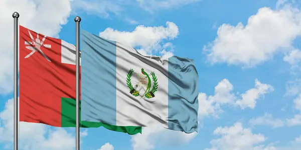 Oman en Guatemala vlag zwaaien in de wind tegen witte bewolkte blauwe hemel samen. Diplomatie concept, internationale betrekkingen. — Stockfoto