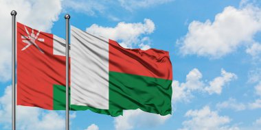 Umman ve Madagaskar bayrağı birlikte beyaz bulutlu mavi gökyüzüne karşı rüzgarda sallayarak. Diplomasi kavramı, uluslararası ilişkiler.