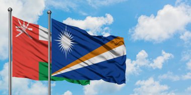 Umman ve Marshall Adaları bayrağı birlikte beyaz bulutlu mavi gökyüzüne karşı rüzgarda sallayarak. Diplomasi kavramı, uluslararası ilişkiler.