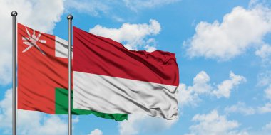 Umman ve Monako bayrağı birlikte beyaz bulutlu mavi gökyüzüne karşı rüzgarda sallayarak. Diplomasi kavramı, uluslararası ilişkiler.