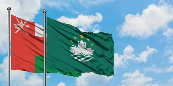 Oman and Macao flag waving in the wind against white cloudy blue sky together. Diplomacy concept, international relations.