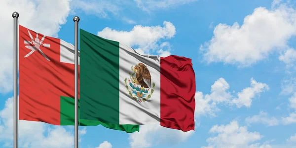 Bandera de Omán y México ondeando en el viento contra el cielo azul nublado blanco juntos. Concepto diplomático, relaciones internacionales . — Foto de Stock