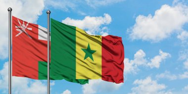 Umman ve Senegal bayrağı birlikte beyaz bulutlu mavi gökyüzüne karşı rüzgarda sallayarak. Diplomasi kavramı, uluslararası ilişkiler.