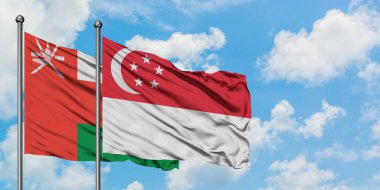 Umman ve Singapur bayrağı birlikte beyaz bulutlu mavi gökyüzüne karşı rüzgarda sallayarak. Diplomasi kavramı, uluslararası ilişkiler.