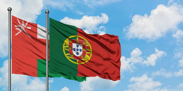 Oman e la bandiera del Portogallo sventolano nel vento contro il bianco cielo blu nuvoloso insieme. Concetto di diplomazia, relazioni internazionali . — Foto Stock
