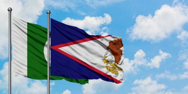 Pakistan ve Amerikan Samoası bayrağı birlikte beyaz bulutlu mavi gökyüzüne karşı rüzgarda sallayarak. Diplomasi kavramı, uluslararası ilişkiler.