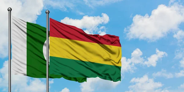 Bandera de Pakistán y Bolivia ondeando en el viento contra el cielo azul nublado blanco juntos. Concepto diplomático, relaciones internacionales . — Foto de Stock