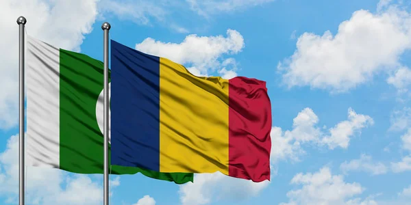 Bandera de Pakistán y Chad ondeando en el viento contra el cielo azul nublado blanco juntos. Concepto diplomático, relaciones internacionales . — Foto de Stock