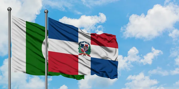 Bandera de Pakistán y República Dominicana ondeando en el viento contra el cielo azul nublado blanco juntos. Concepto diplomático, relaciones internacionales . — Foto de Stock