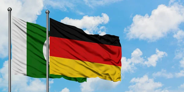 Pakistan och Tyskland sjunker vifta i vinden mot vit grumlig blå himmel tillsammans. Diplomatisk koncept, internationella relationer. — Stockfoto
