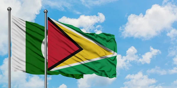 Bandera de Pakistán y Guyana ondeando en el viento contra el cielo azul nublado blanco juntos. Concepto diplomático, relaciones internacionales . — Foto de Stock