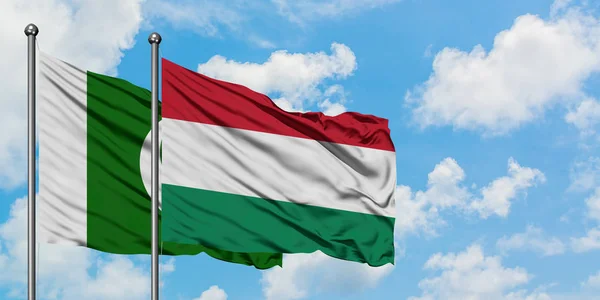 Bandera de Pakistán y Hungría ondeando en el viento contra el cielo azul nublado blanco juntos. Concepto diplomático, relaciones internacionales . — Foto de Stock