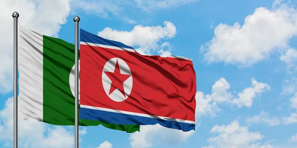 Pakistan en Noord-Korea vlag zwaaien in de wind tegen witte bewolkte blauwe hemel samen. Diplomatie concept, internationale betrekkingen. — Stockfoto