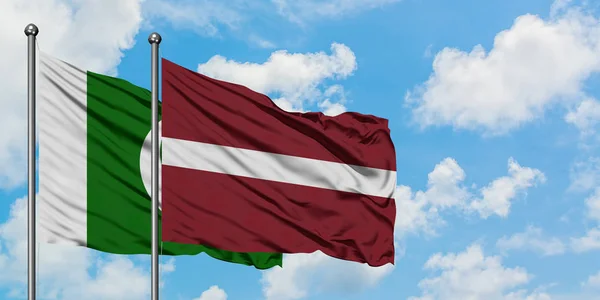Pákistán a Lotyšská vlajka mávali ve větru proti bíle zatažené modré obloze. Diplomacie, mezinárodní vztahy. — Stock fotografie