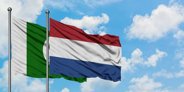 Pakistan e Paesi Bassi bandiera sventolando nel vento contro bianco cielo blu nuvoloso insieme. Concetto di diplomazia, relazioni internazionali . — Foto Stock