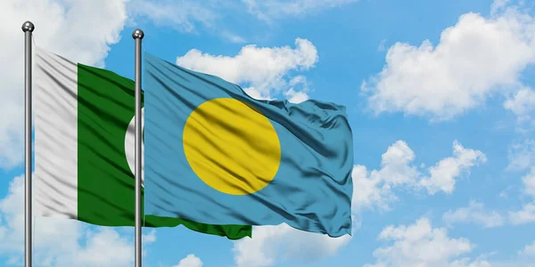 Bandera de Pakistán y Palau ondeando en el viento contra el cielo azul nublado blanco juntos. Concepto diplomático, relaciones internacionales . — Foto de Stock