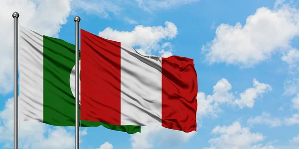 Bandera de Pakistán y Perú ondeando en el viento contra el cielo azul nublado blanco juntos. Concepto diplomático, relaciones internacionales . —  Fotos de Stock