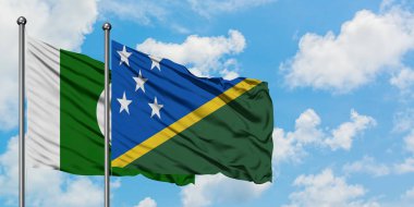 Pakistan ve Solomon Adaları bayrağı birlikte beyaz bulutlu mavi gökyüzüne karşı rüzgarda sallayarak. Diplomasi kavramı, uluslararası ilişkiler.